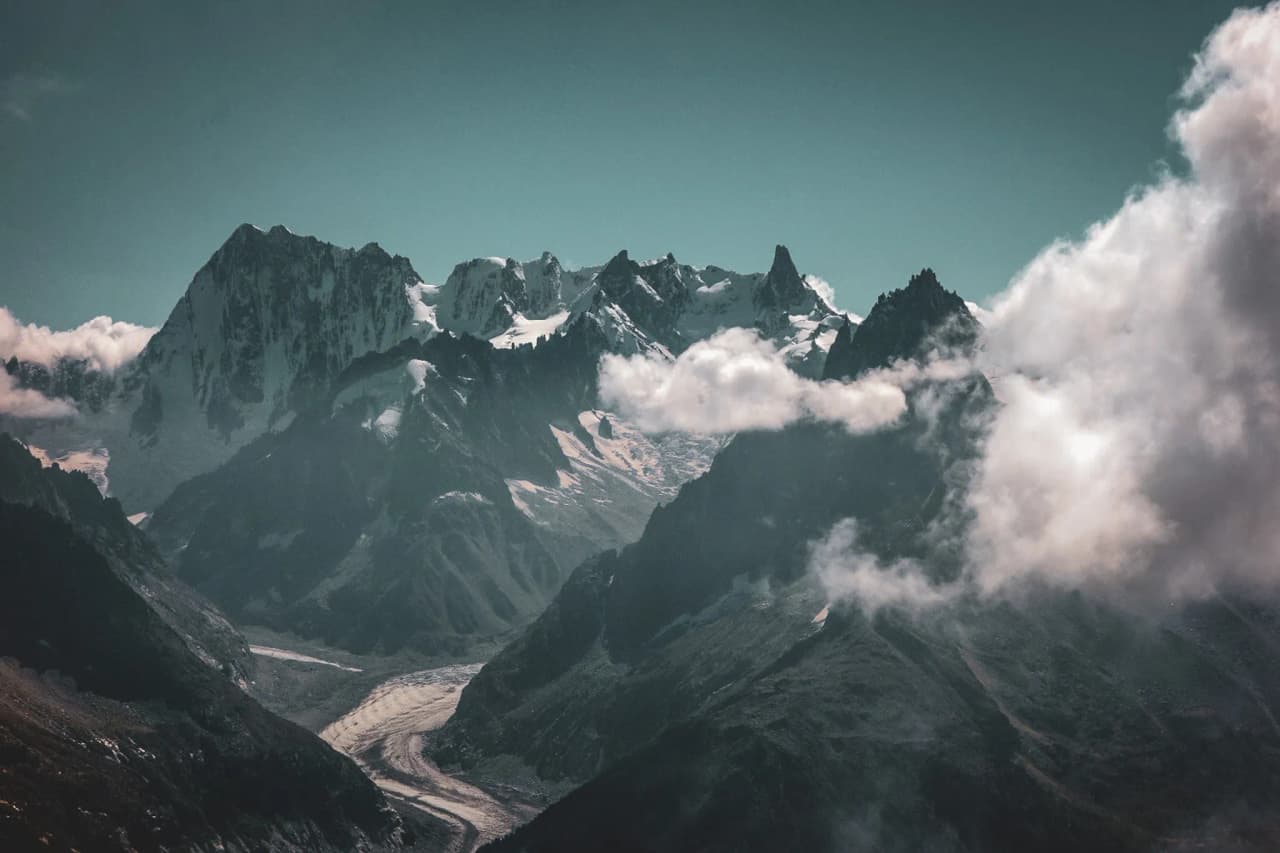 Majestic peaks and glacial valleys under a blue sky, an invitation to mountain adventure.