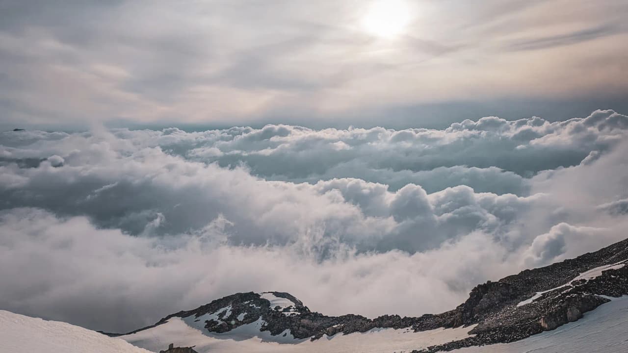 A panoramic view of the clouds above the snow-capped peaks – an invitation to an alpine adventure.