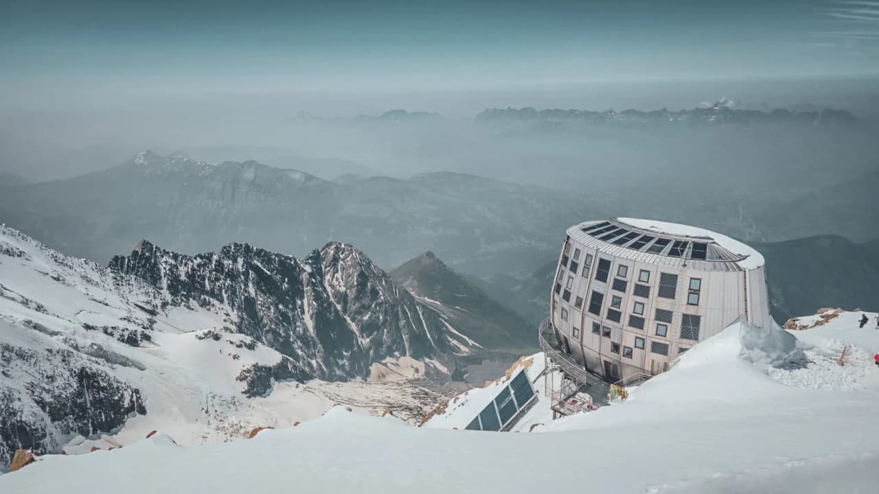 Spectaculair uitzicht op de Mont Blanc, met een moderne hut op de besneeuwde toppen.