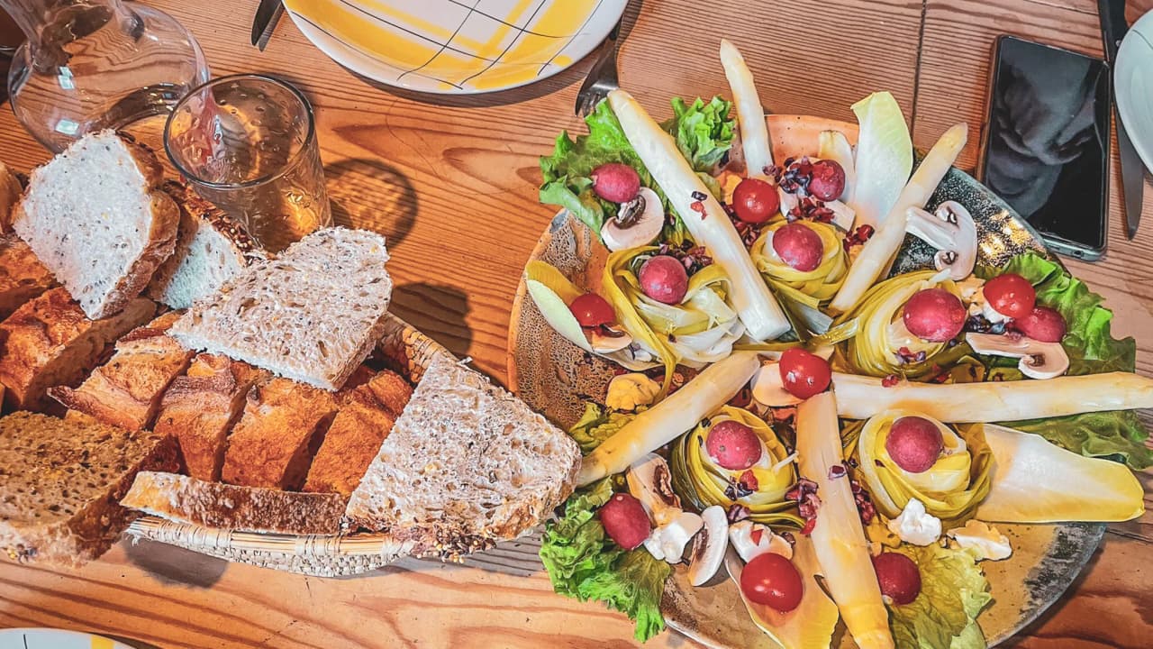A colourful dish with salad, tomatoes and fresh bread on a wooden table, inviting you to explore.