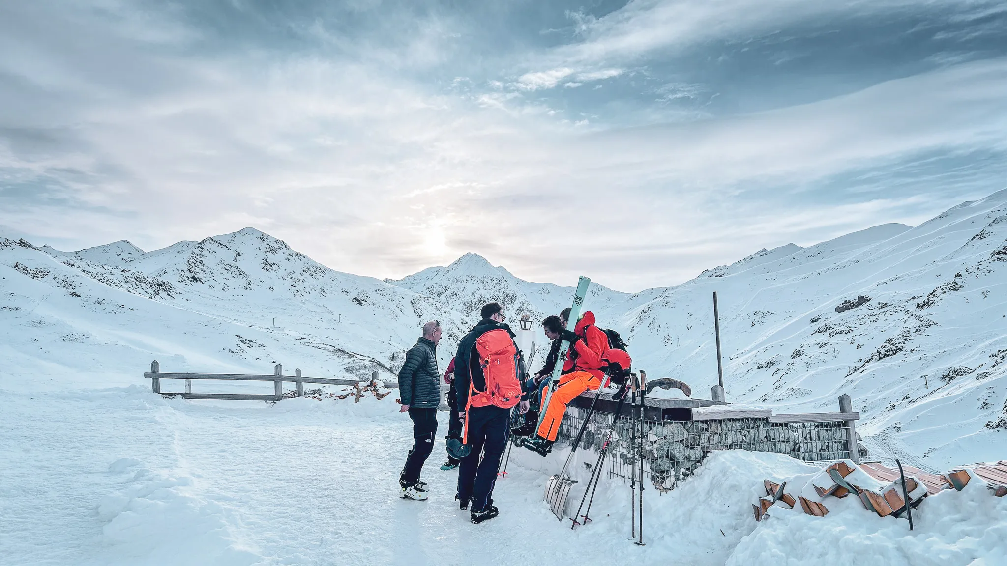 Groupe de skieurs au col du Grand-Saint-Bernard, avec montagnes enneigées en arrière-plan.