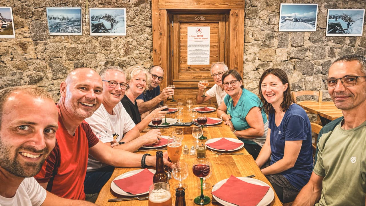 A smiling group around a table, ready to enjoy mountain dishes after a hike in the Vosges.