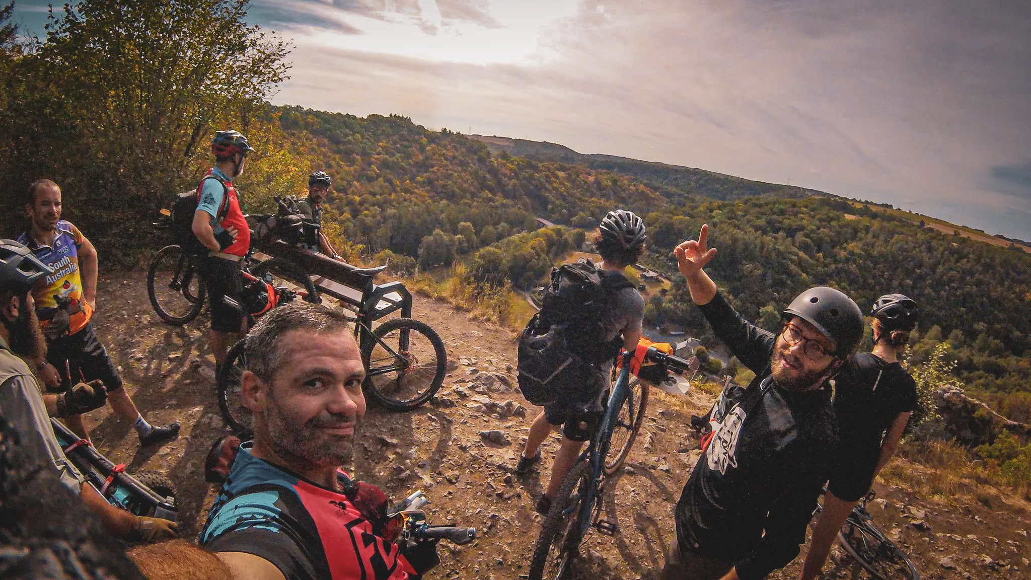 Groupe d'aventuriers en VTT admirant un paysage sauvage au bord de la vallée de la Lesse.