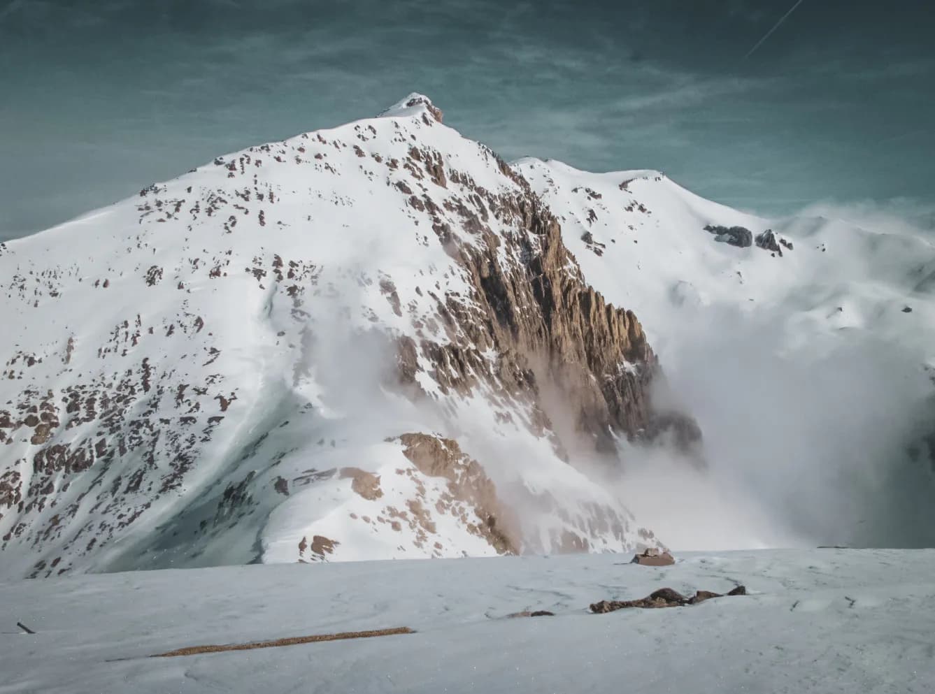 Majestic snow-capped mountains, caressing mist, an invitation to alpine adventure.