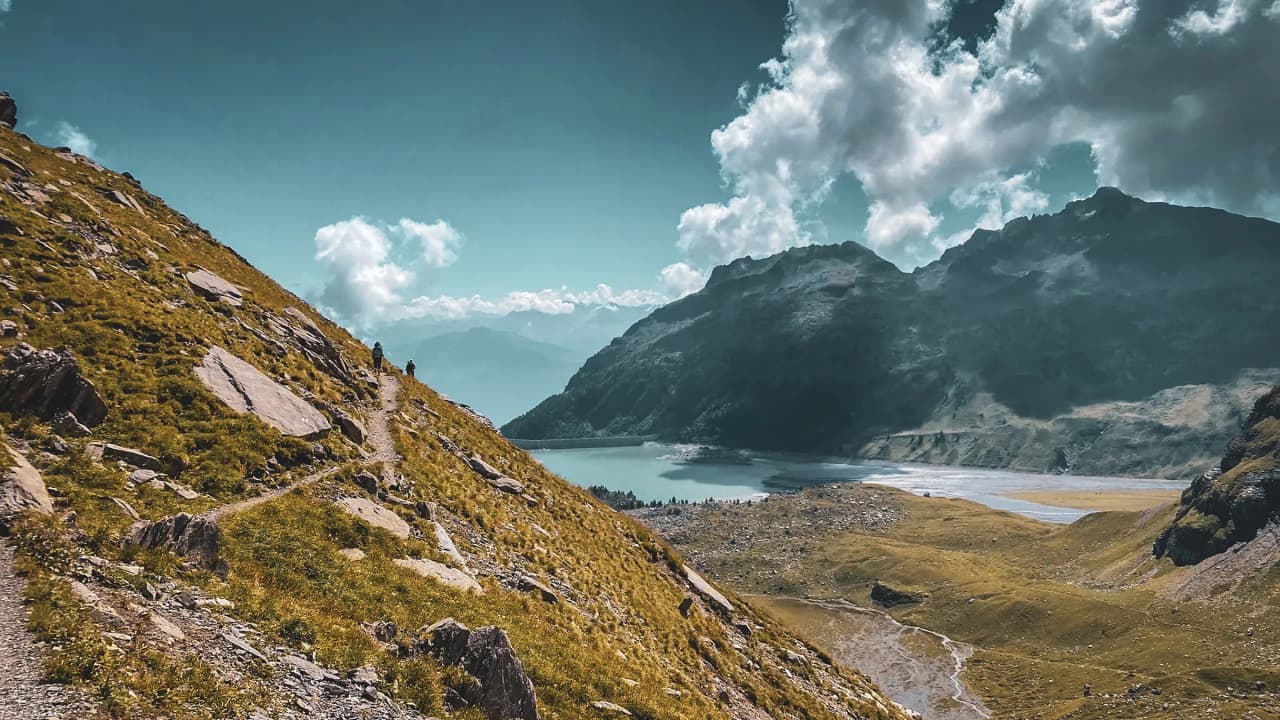 A scenic trail leading to turquoise lakes, surrounded by the majestic peaks of the Alps.