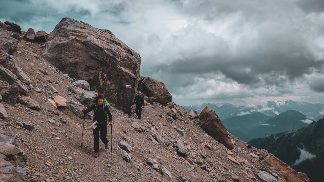 Hikers on a steep path in the Dents du Midi, surrounded by majestic Alpine scenery.