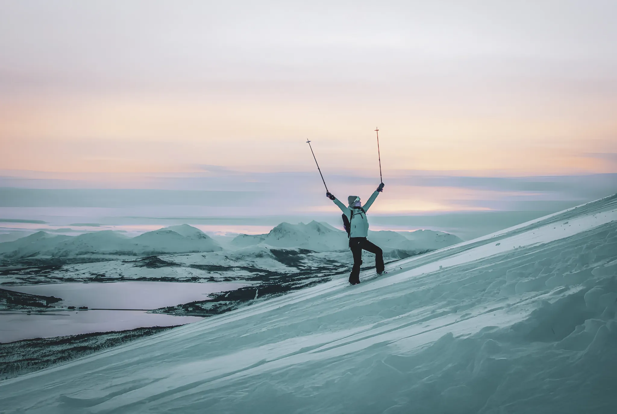 Een avonturier op sneeuwschoenen, op de top van een witte pas, bewondert de zonsondergang over ijzige fjorden.