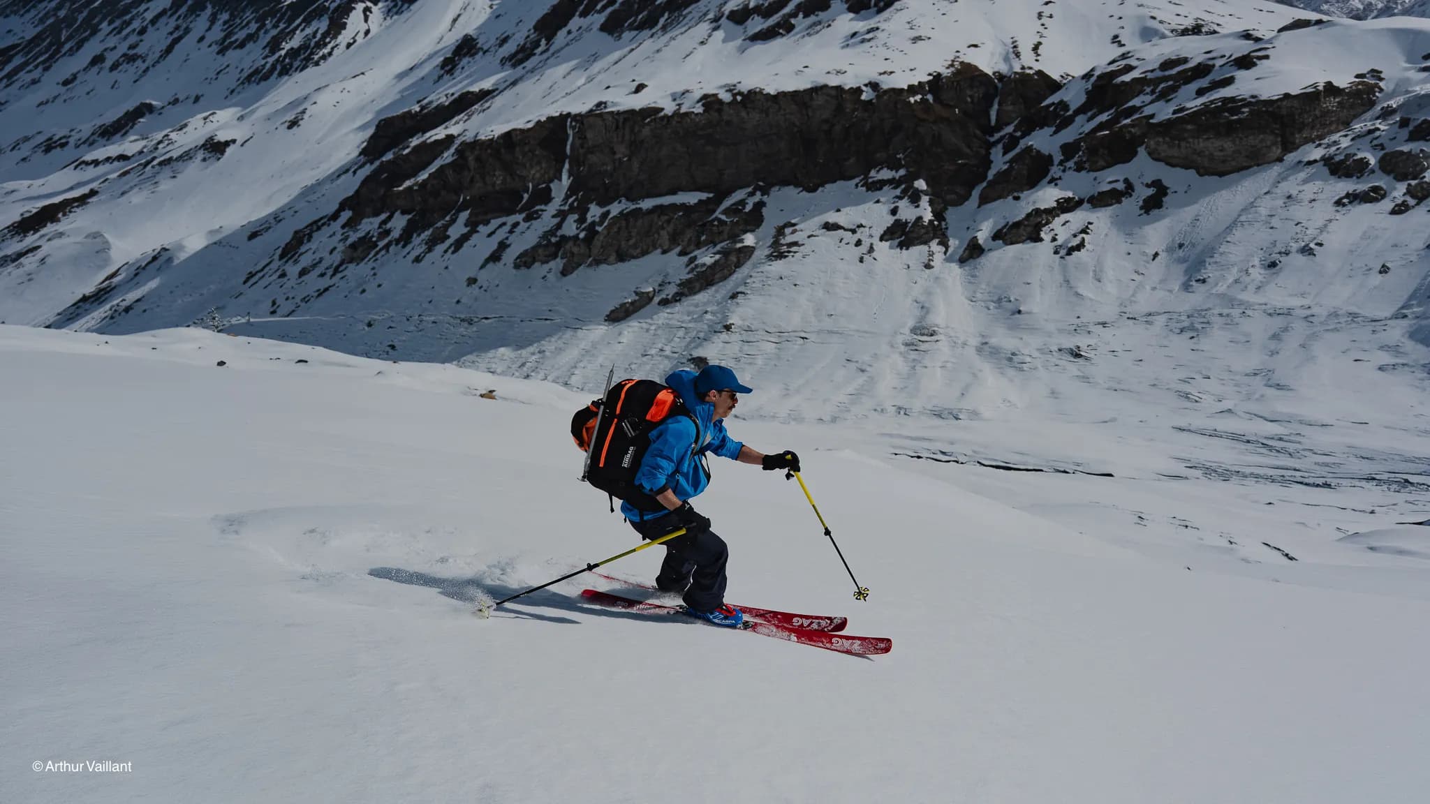 A skier hurtling down snow-covered slopes, surrounded by majestic Alpine mountains.