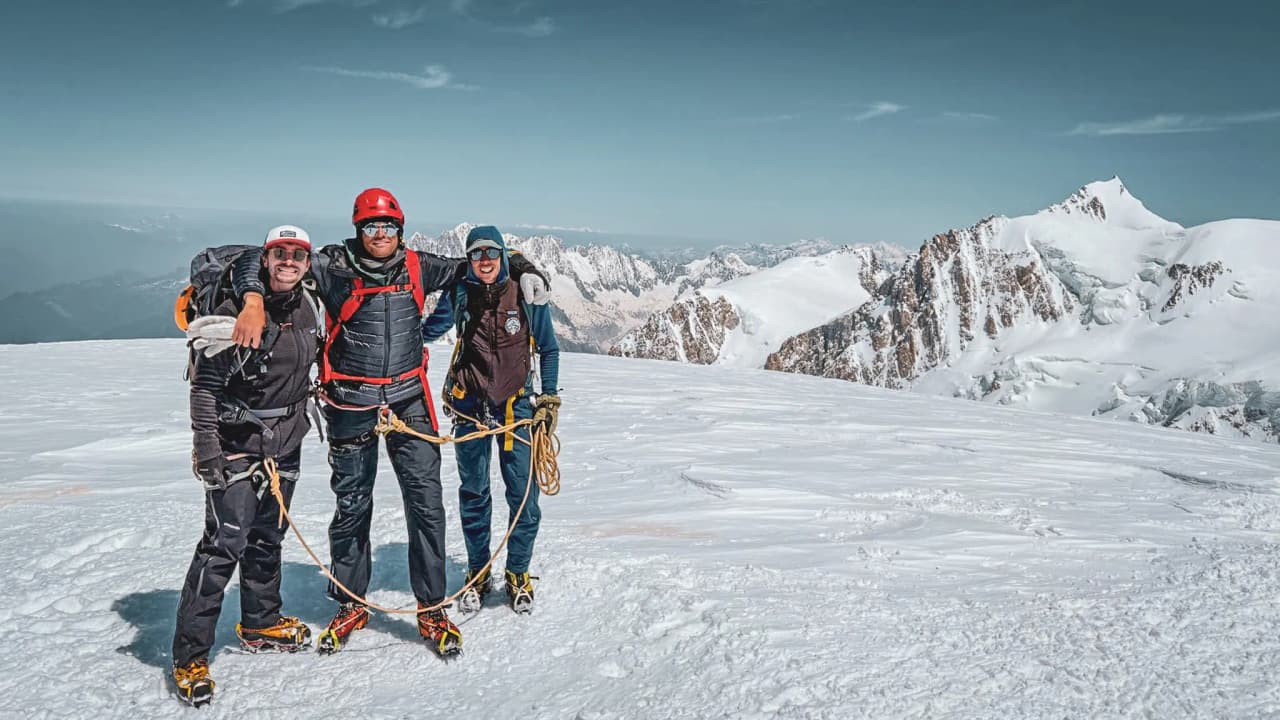 Drie triomferende bergbeklimmers op de top van de Mont Blanc, omringd door majestueuze sneeuwlandschappen.