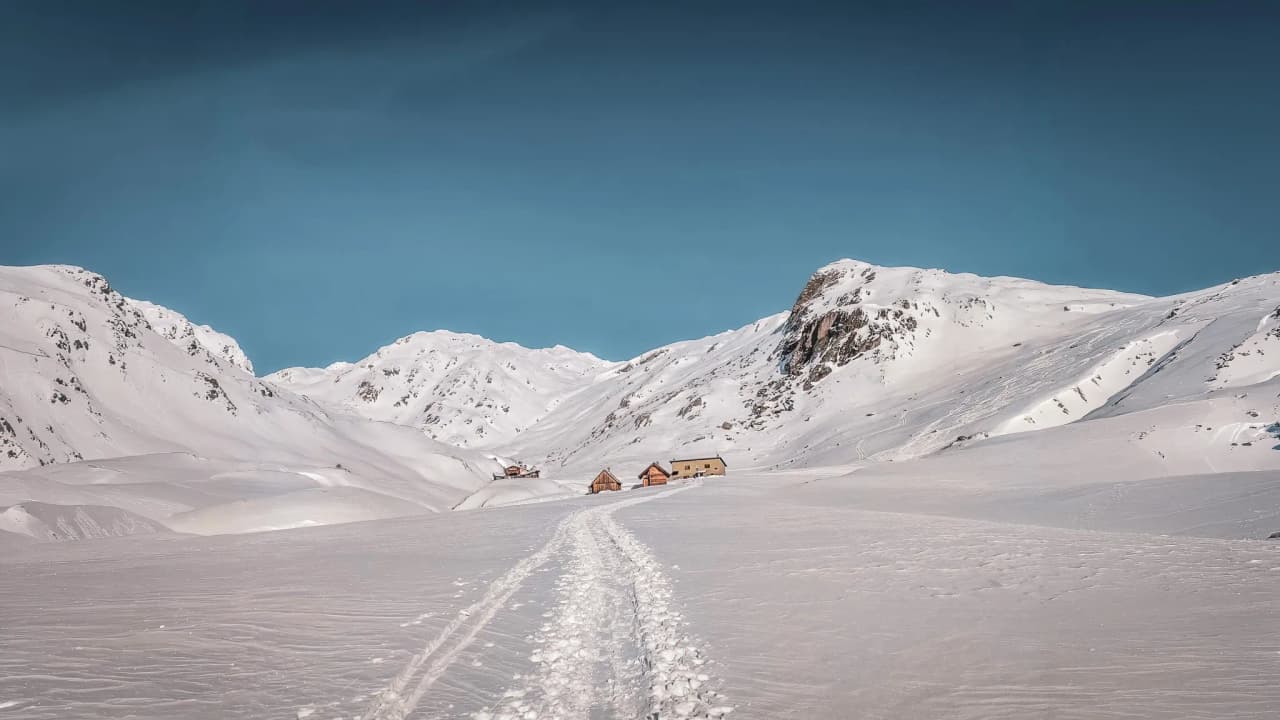 A spectacular winter landscape featuring snow-capped mountains and picturesque mountain huts.
