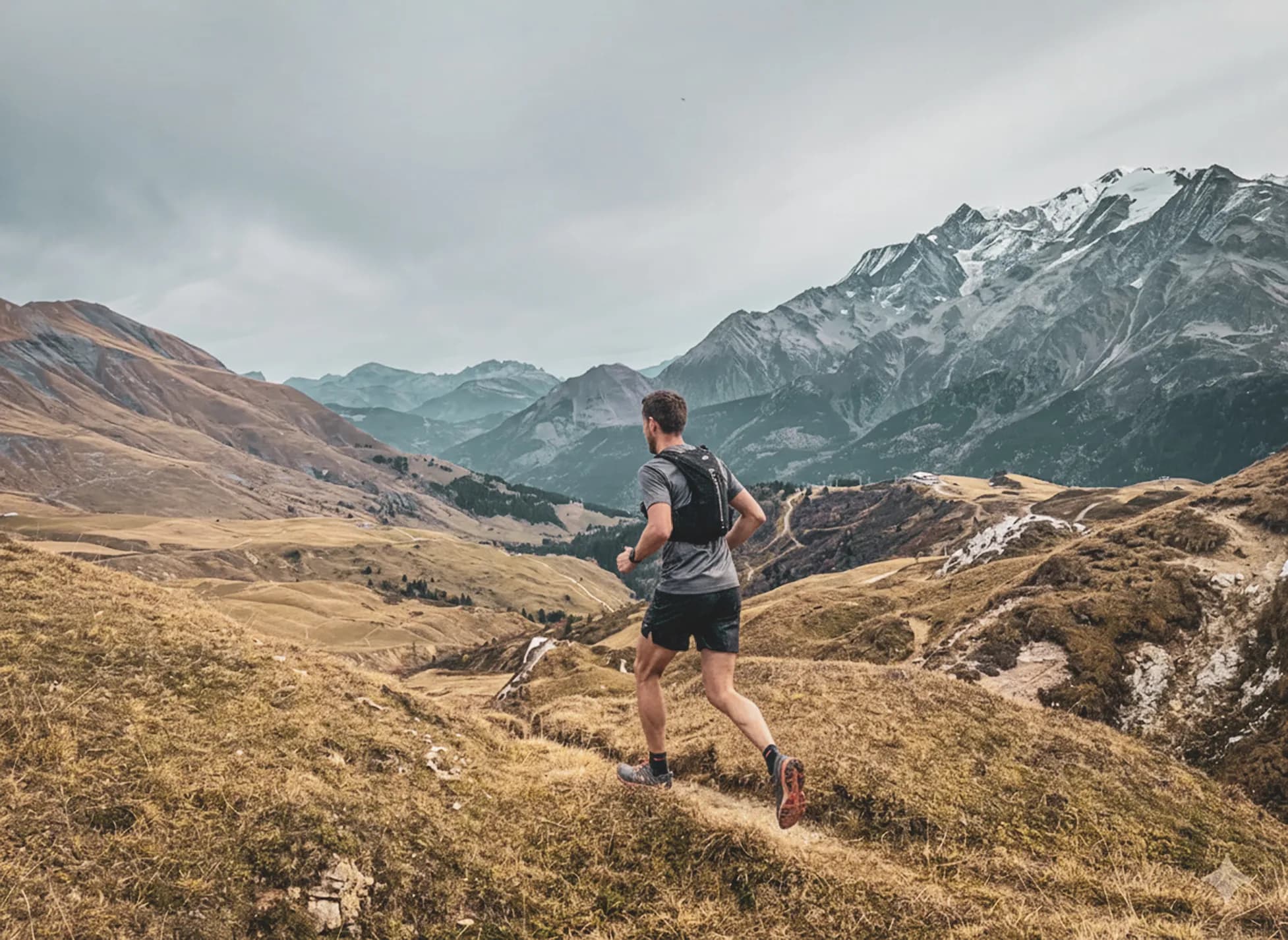 Een hardloper doorkruist majestueuze Alpenlandschappen, tussen bergen en groene valleien.