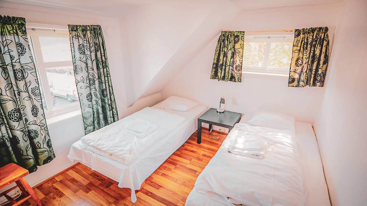 Lichte kamer met twee eenpersoonsbedden en gebloemde gordijnen, perfect voor een Scandinavisch avontuur.