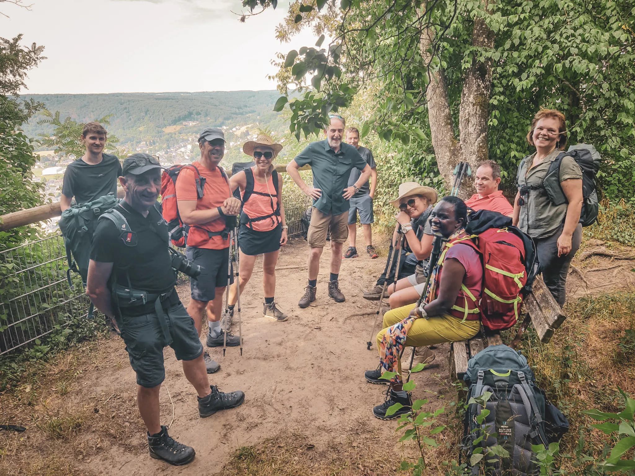 Groupe de randonneurs souriants en pause dans la Petite Suisse luxembourgeoise verdoyante.