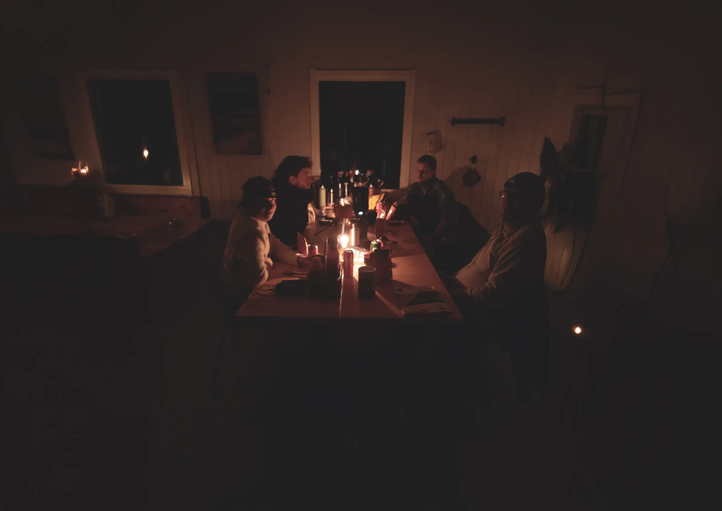 A group of travellers around a candlelit table, a warm atmosphere in Lapland.
