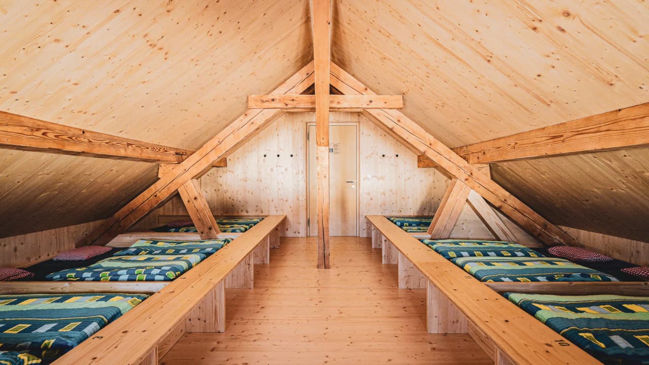 The warm interior of an alpine Mountain hut with cosy beds, perfect for a stay after a mountain adventure.