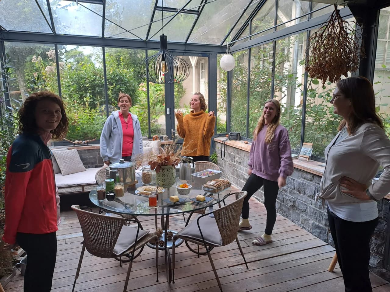 A group of happy women at a yoga retreat, surrounded by greenery in a bright veranda.