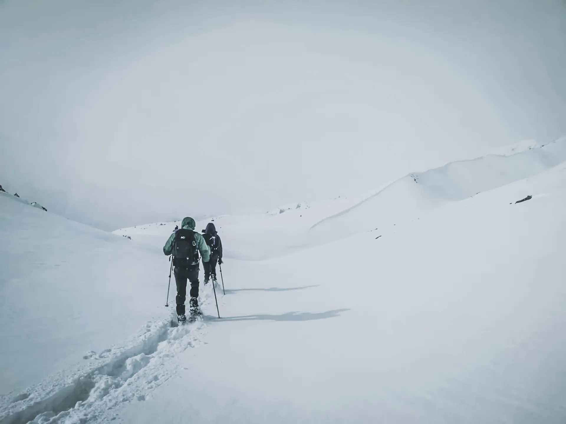 Two hikers make their way along a snow-covered path, discovering enchanting Alpine landscapes.