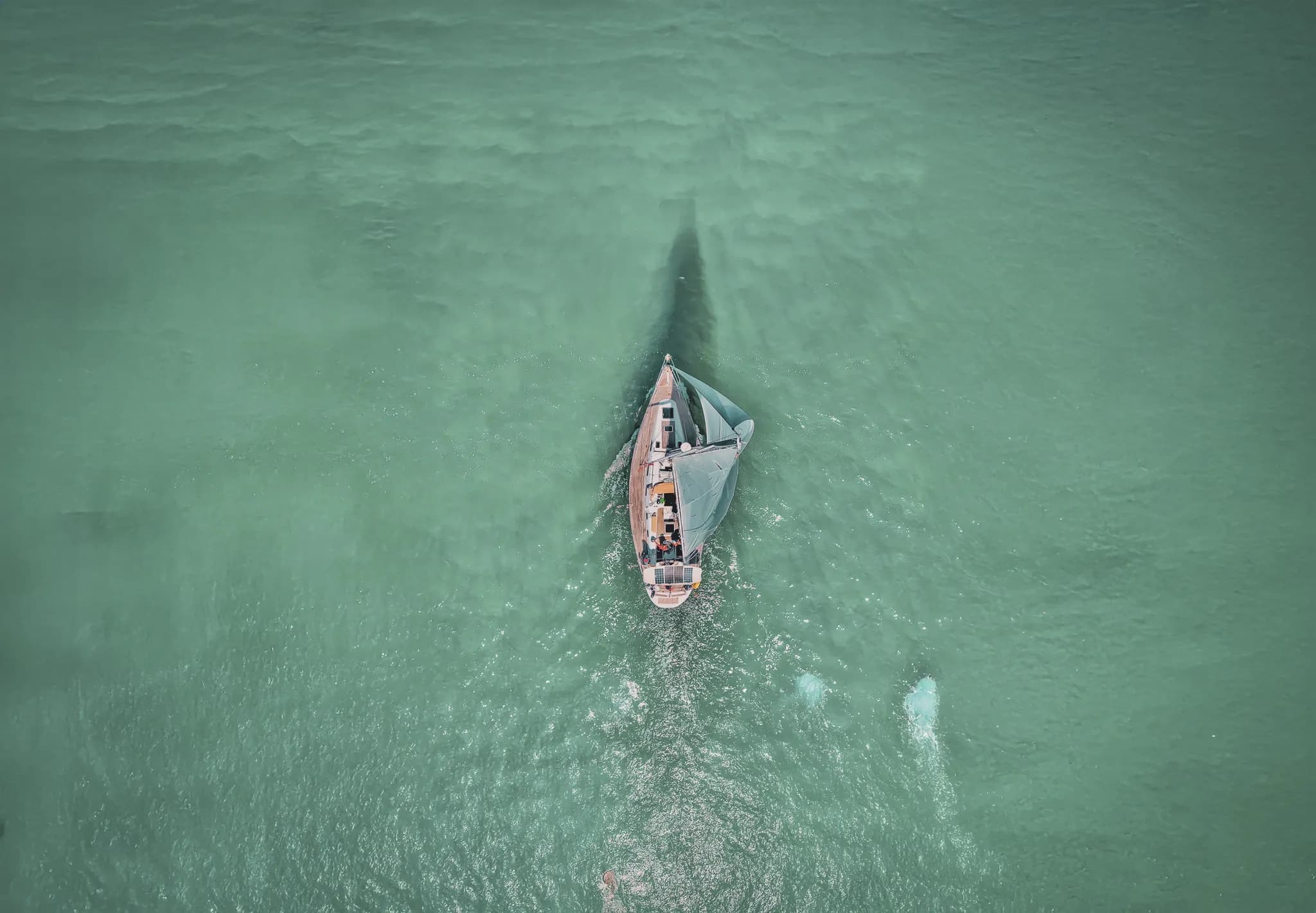 Un voilier glisse sur des eaux turquoises, invitant à l'évasion en Bretagne.