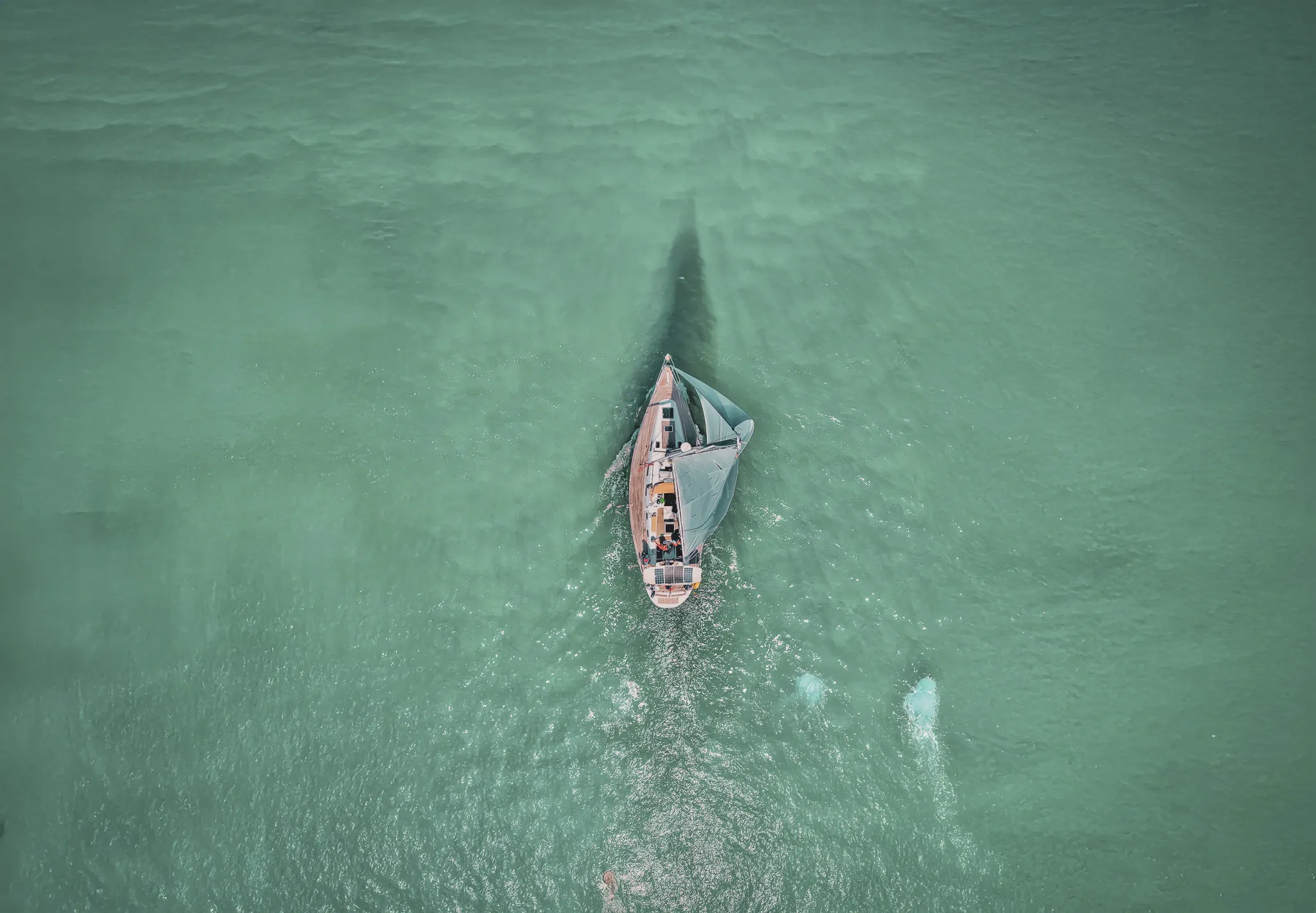 Un voilier glisse sur des eaux turquoises, invitant à l'évasion en Bretagne.