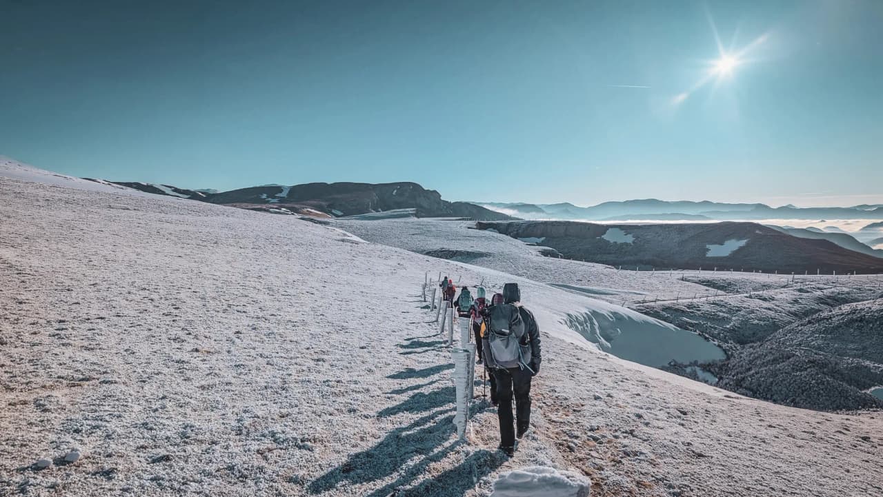Groupe de randonneurs en raquettes sur un paysage enneigé pittoresque dans le Vercors.