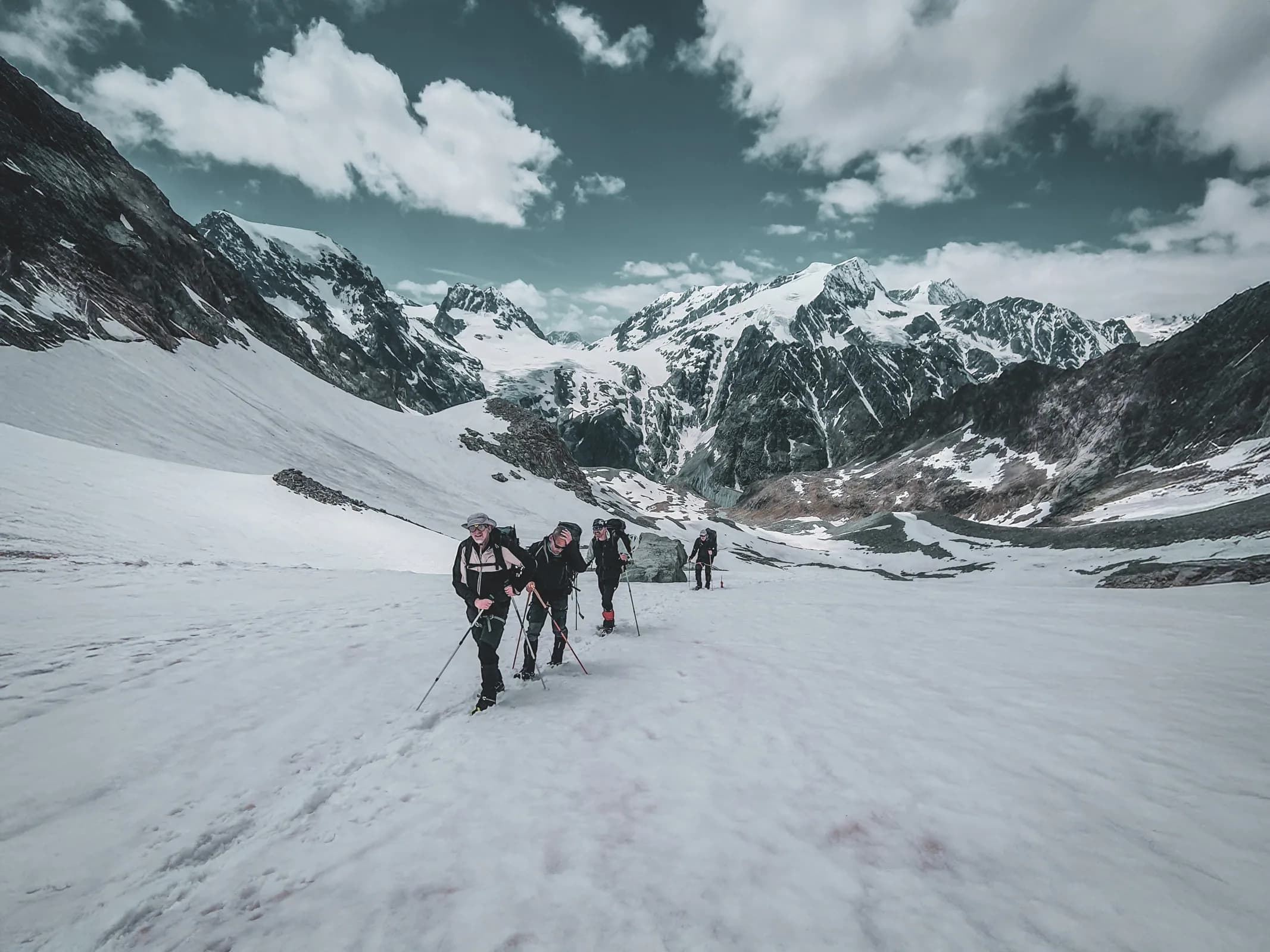 A group of hikers on a glacier, surrounded by majestic Alpine peaks under clear skies.