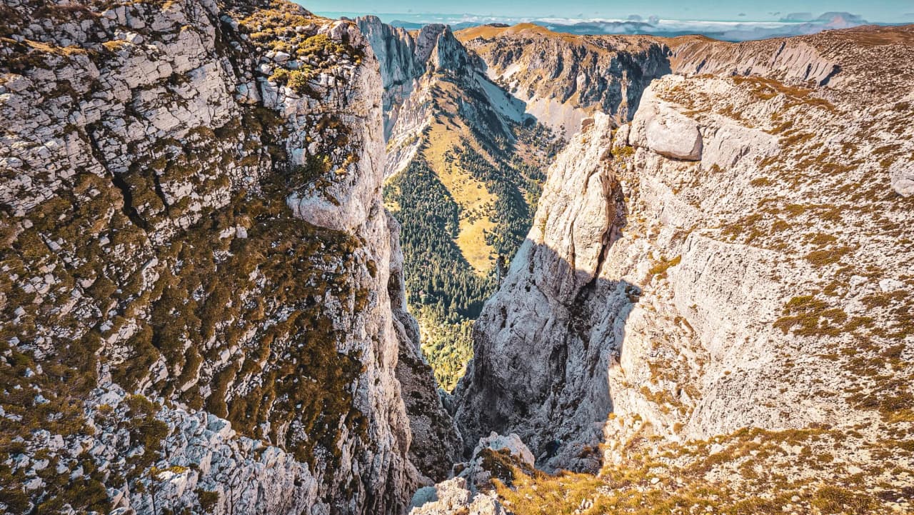 Een majestueus panorama van de Mont Aiguille, rotswanden en een groene, zonovergoten vallei.