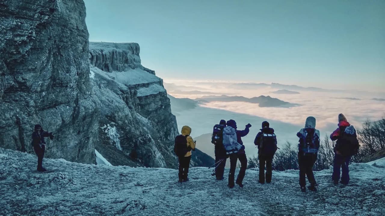 Groupe de randonneurs en raquettes avec vue sur les montagnes enneigées et un ciel éclatant.