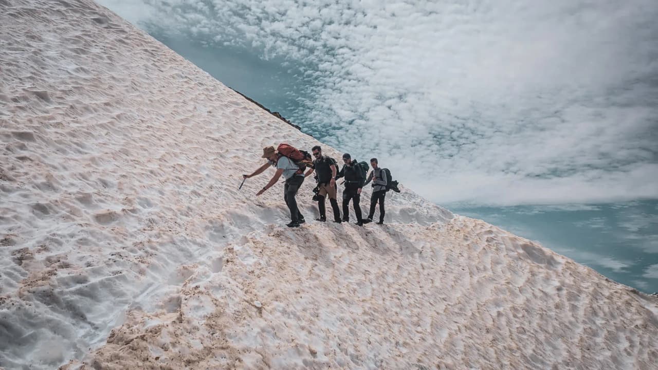 A group of mountaineers tackling the snow-covered ascent of Mont Blanc under cloudy skies.