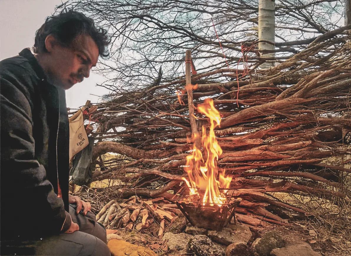 An adventurer meditating by a campfire, surrounded by the wilderness of the Vercors.