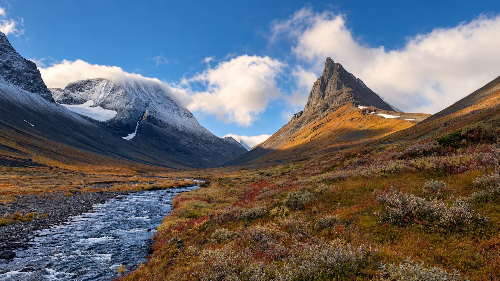 Een ongerepte vallei in Zweeds Lapland, majestueuze bergen, een beekje en kleurrijke landschappen.
