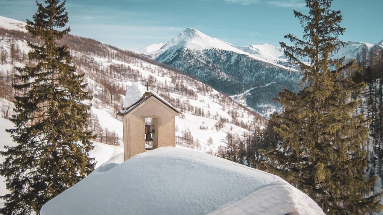 Un paysage enneigé du Queyras avec des montagnes majestueuses et un charmant clocher.