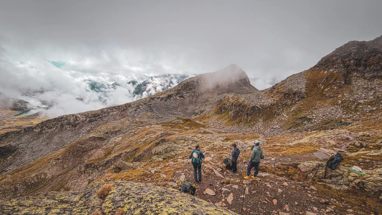 Five adventurers gaze at the peaks of Monte Rosa under a cloudy sky.