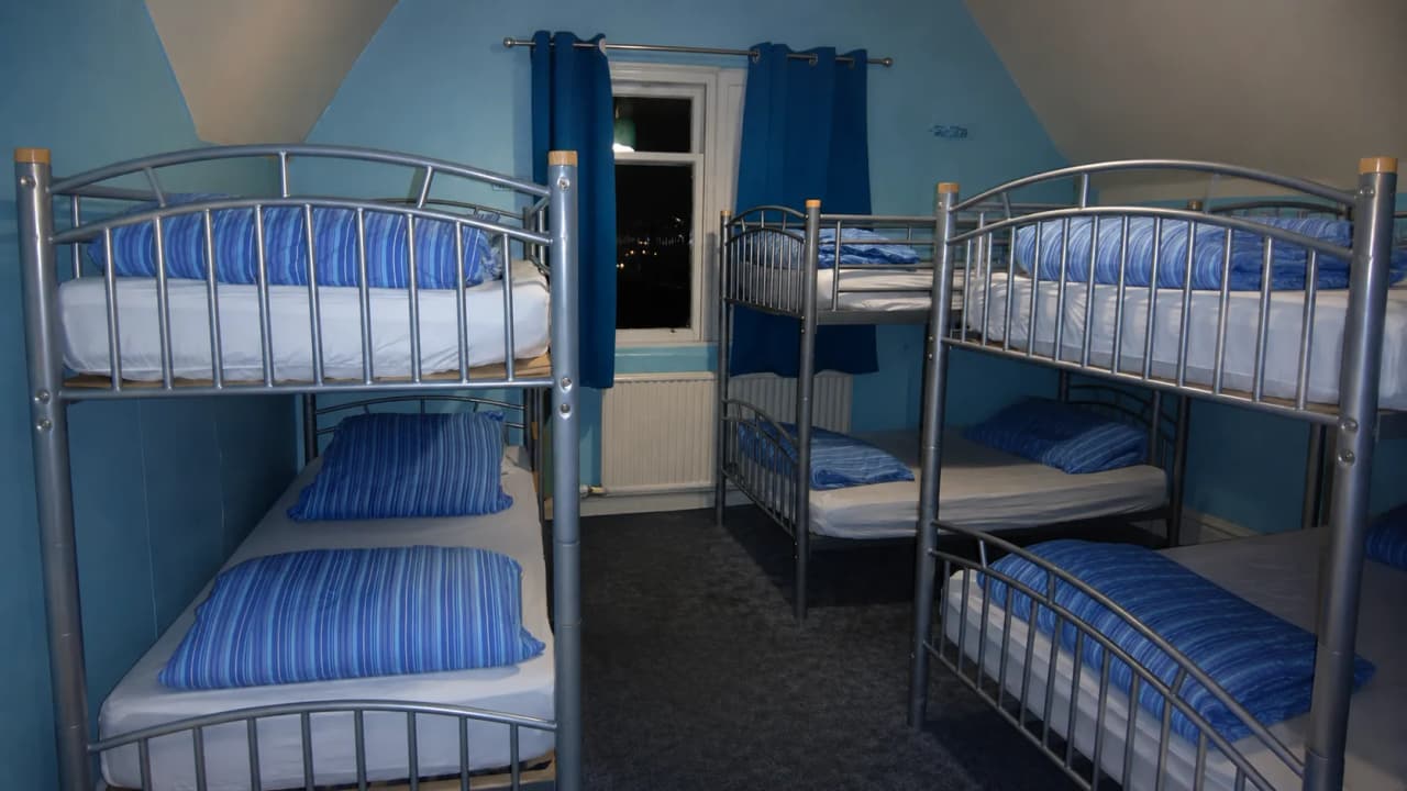 Herbergkamer met stapelbedden en blauw gestreepte kussens, perfect voor een bergavontuur.