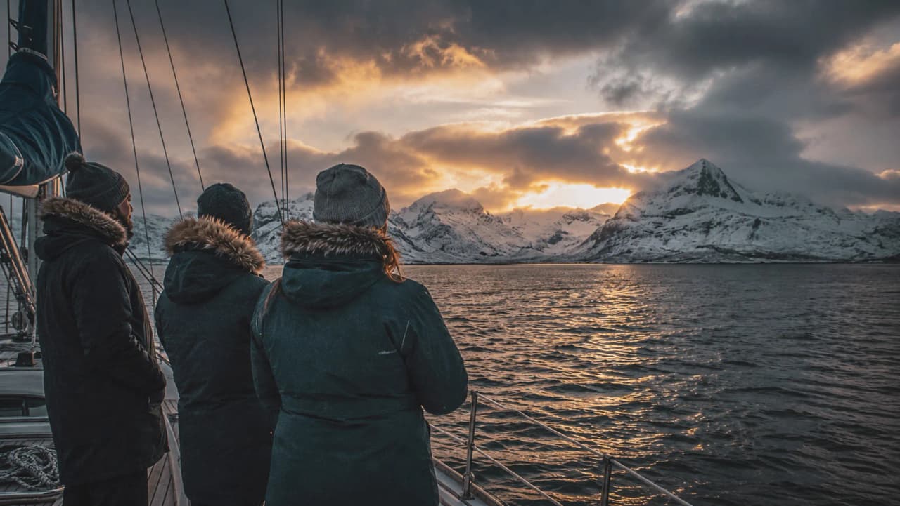 Een zeiltocht door de fjorden van Tromsø, waarbij je kunt genieten van de zonsondergang boven de besneeuwde bergen.