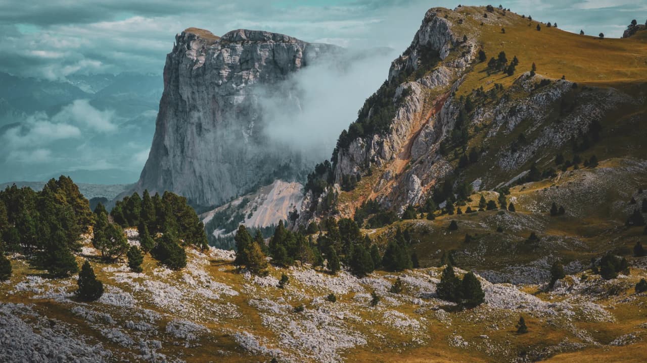 The majestic scenery of the Vercors High Plateaux, between mountains, clouds and lush green forests.