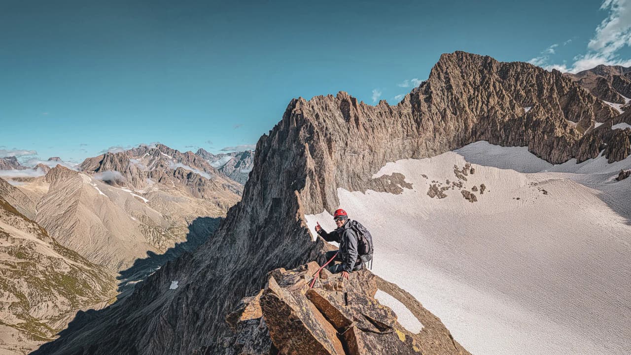 Un alpiniste au sommet, entouré de montagnes majestueuses et de glaciers éclatants, invitant à l'aventure.