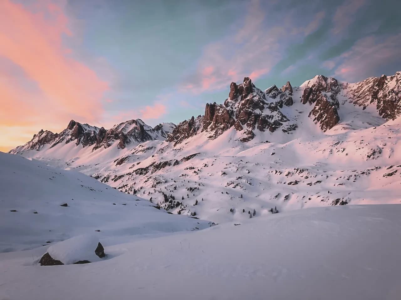 Besneeuwde bergen bij zonsopgang, een pastelkleurige hemel, een betoverende sfeer voor een winteravontuur.