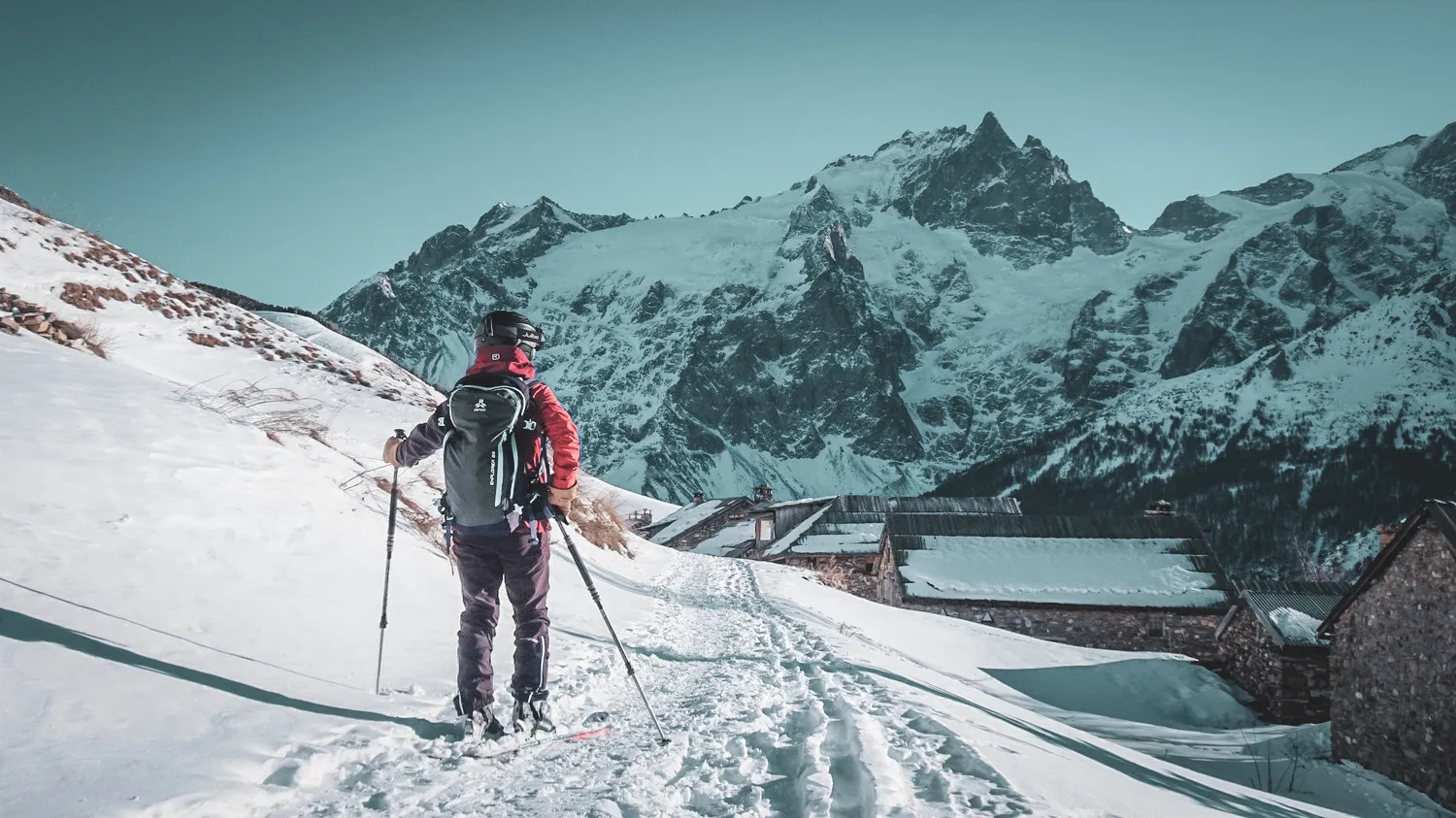 An adventurous solo skier on a snowy trail in front of majestic mountains.