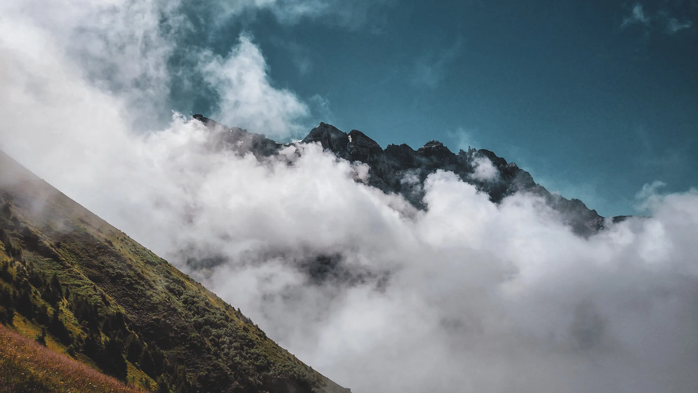 Vue spectaculaire des Dents du Midi entourées de nuages, offrant un panorama alpin époustouflant.