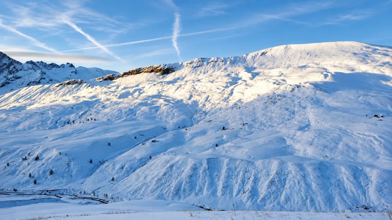 A magnificent alpine panorama with snow-capped mountains against a brilliant blue sky.