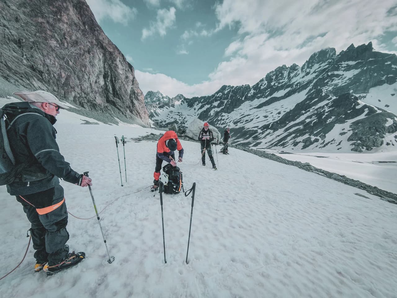 Group of climbers on a glacier, with majestic Alpine peaks in the background.