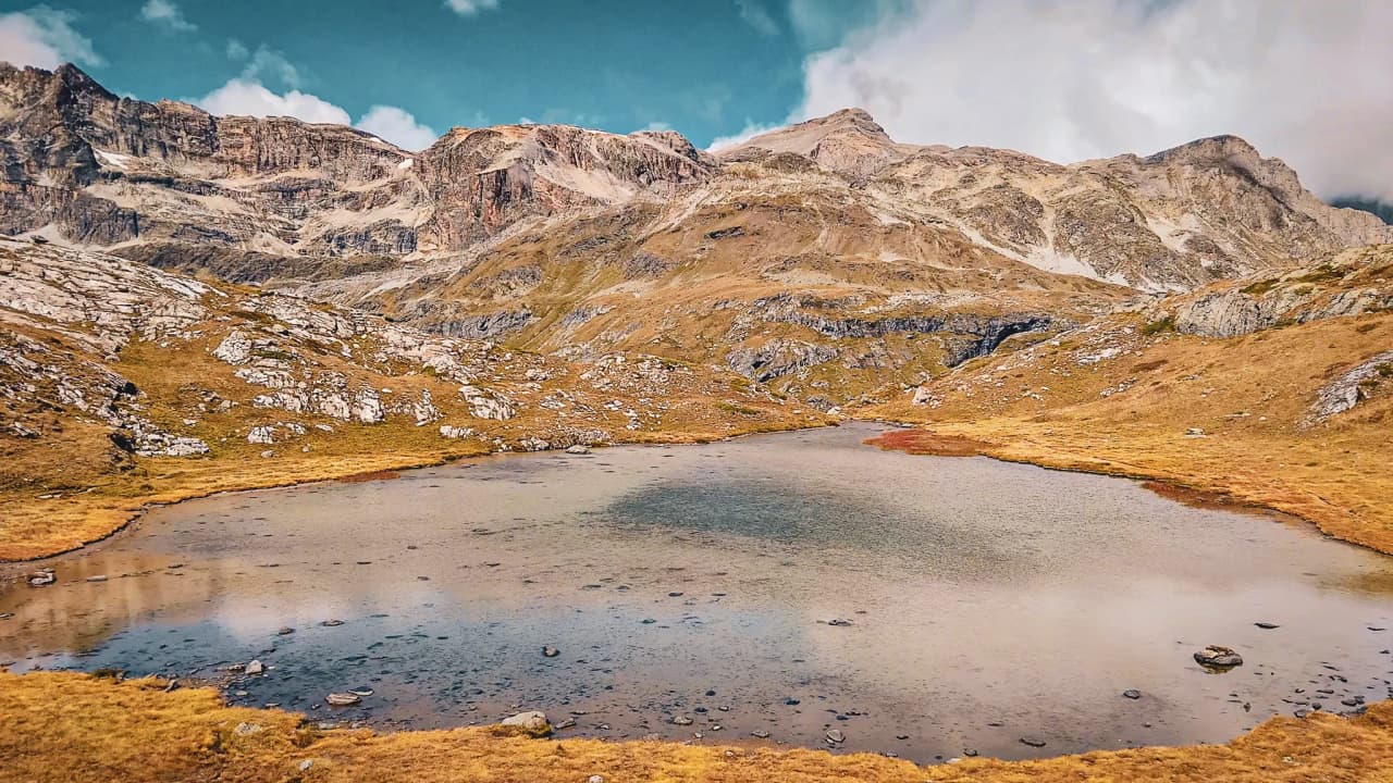 Een vredig meer omringd door ruige bergen, een weerspiegeling van de blauwe lucht, een uitnodiging tot avontuur.