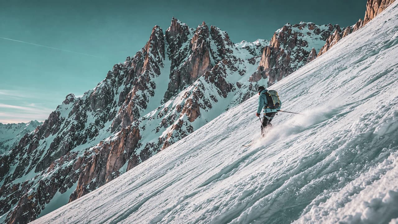 Ski de randonnée sur les pentes majestueuses du Mont Blanc, avec des sommets enneigés en arrière-plan.