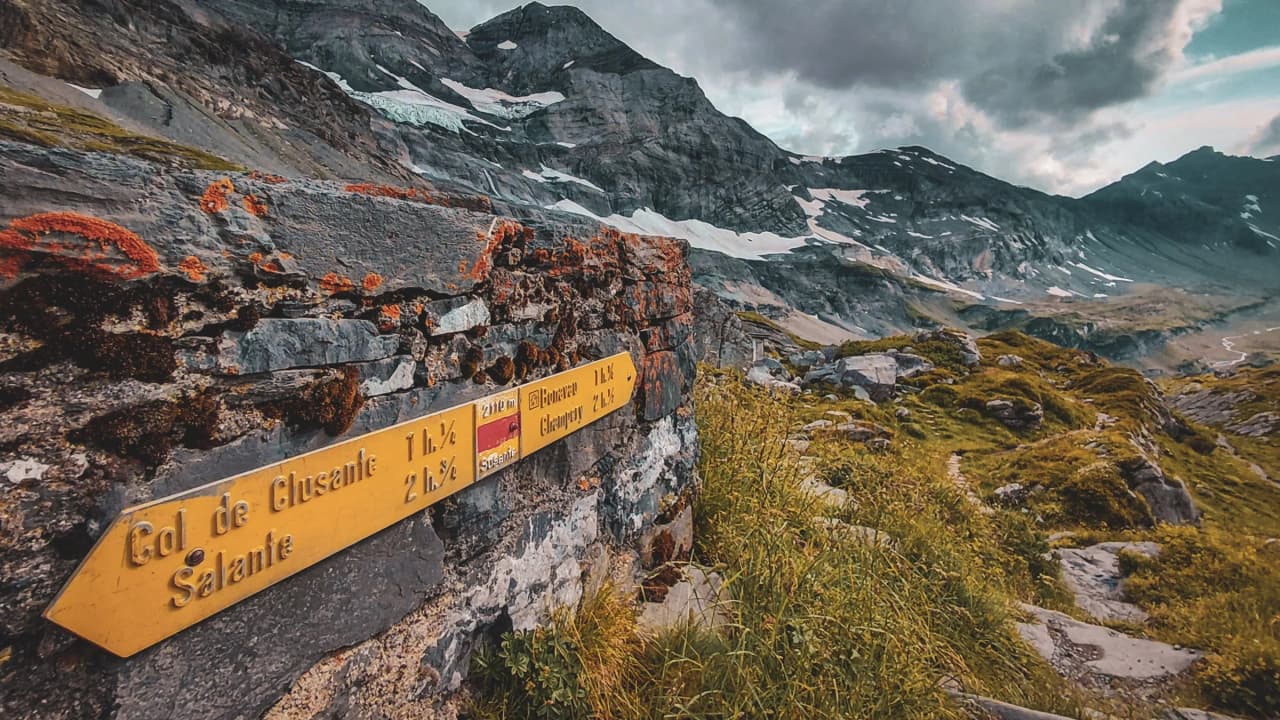 A mountain trail with signposts, majestic alpine scenery and turquoise lakes.
