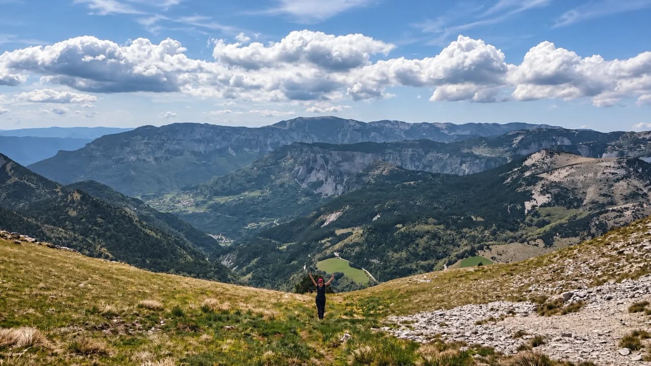 Een gelukkige wandelaar staat op de hoogvlakten van de Vercors, met uitzicht op een majestueus landschap.