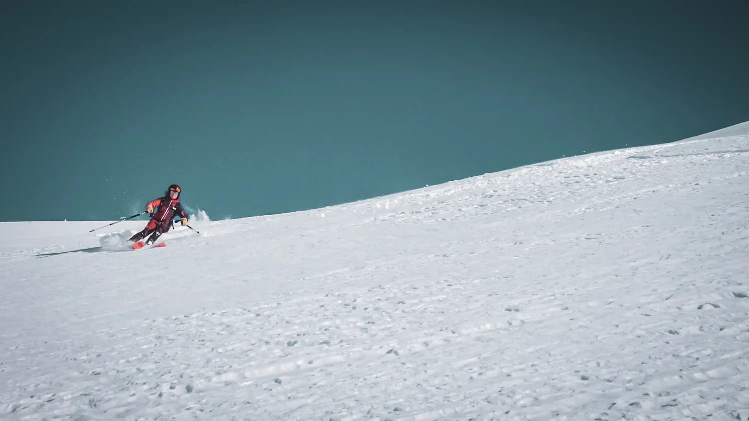 Ski touring on a virgin slope, snow-covered landscape under a brilliant blue sky.