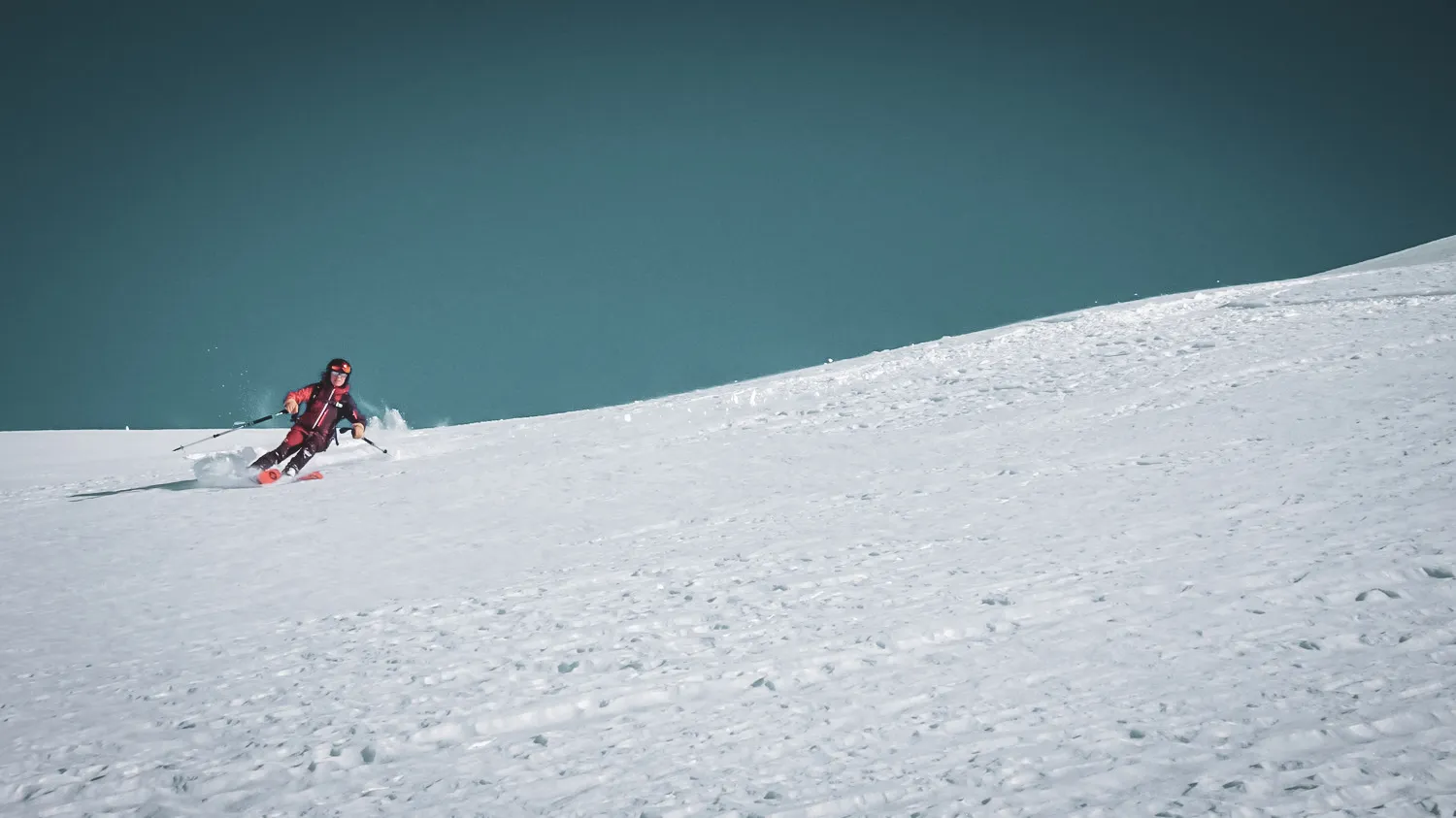 Ski touring on a virgin slope, snow-covered landscape under a brilliant blue sky.