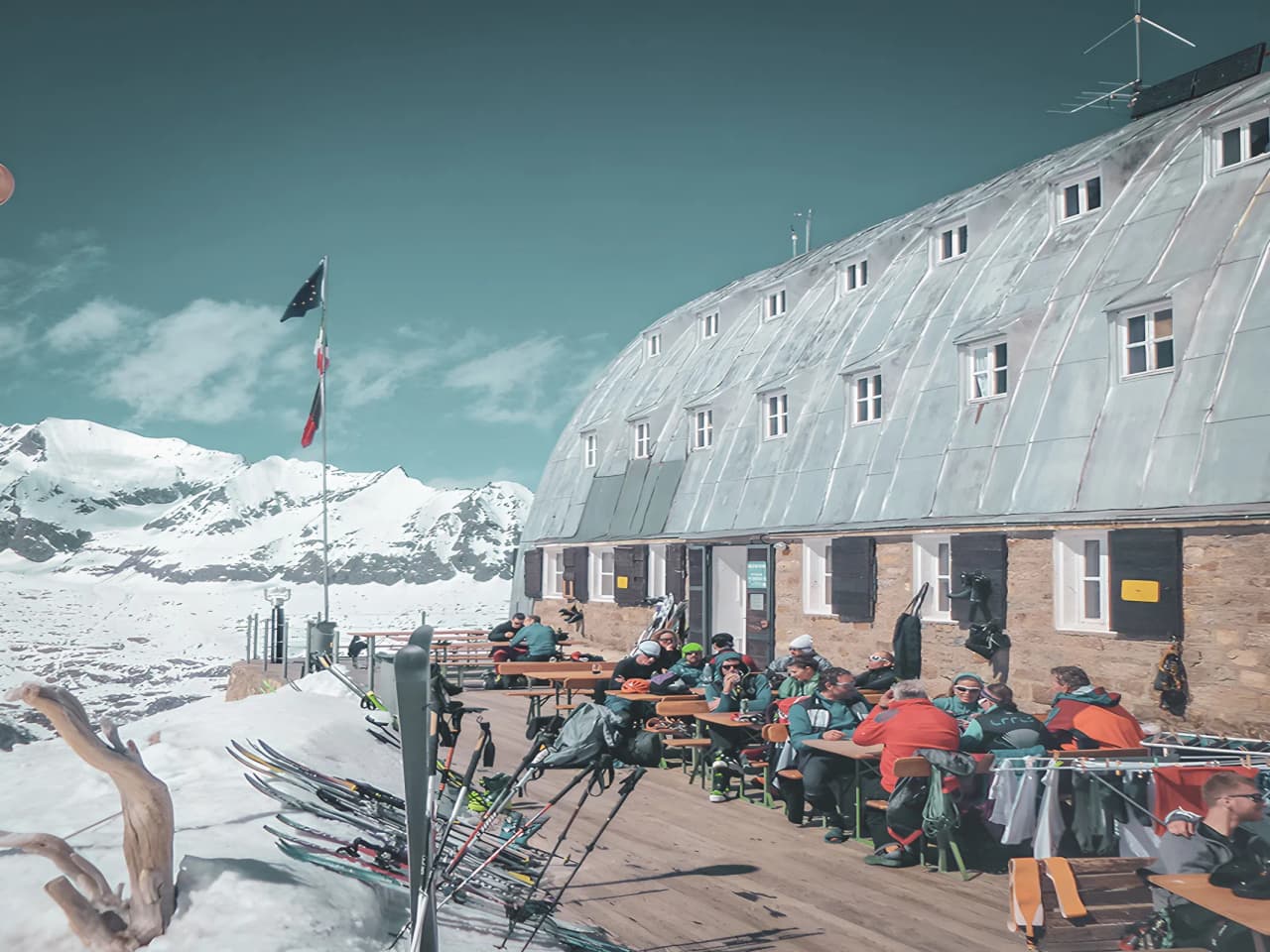 Refuge alpin ensoleillé, skieurs se reposent avec vue spectaculaire sur les sommets enneigés.