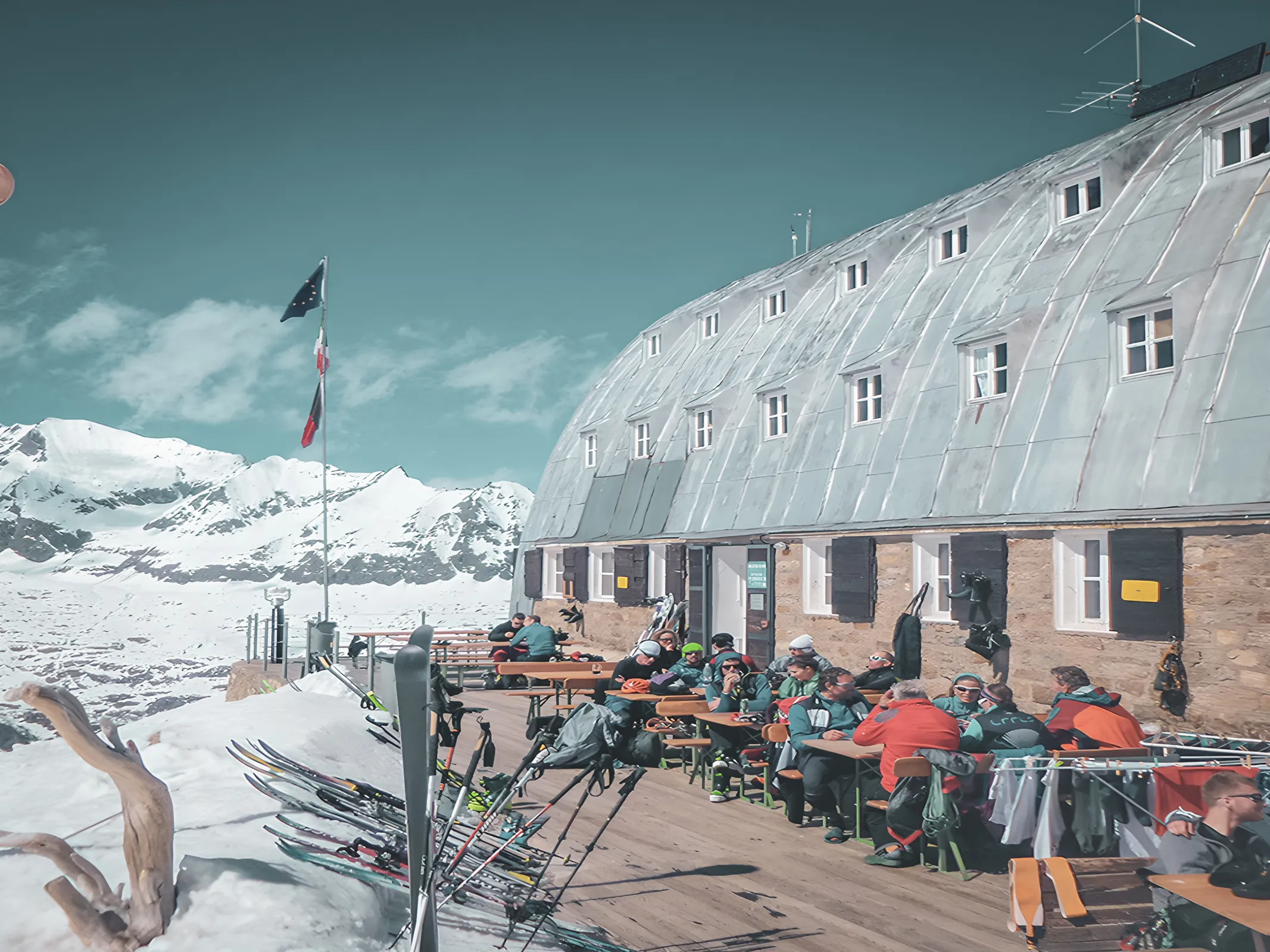 Refuge alpin ensoleillé, skieurs se reposent avec vue spectaculaire sur les sommets enneigés.