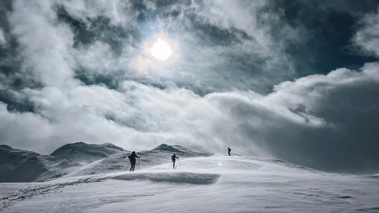 Ski de randonnée sur des crêtes enneigées, sous un ciel dramatique et lumineux. Évasion alpine.
